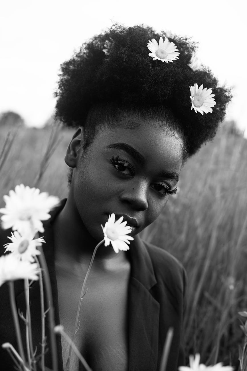 grayscale photo of woman with daisy on ear